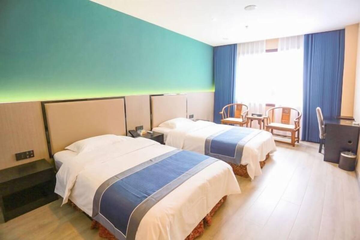 Ein Hotelzimmer mit zwei Betten, einem Schreibtisch und einem Stuhl.