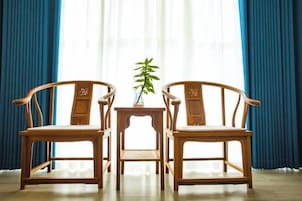 Dos sillas de madera con asientos y respaldos acolchados, colocadas sobre una pequeña mesa con una planta en maceta.