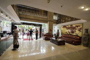 A hotel lobby with a reception desk, a seating area with sofas, and a large decorative wall. - Wuyi Hotel (Sanming)