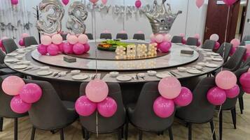 Mesa redonda com balões cor de rosa e balões prateados, e um letreiro com o número '35'.