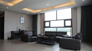 A modern living room with a sofa set, a coffee table, and a desk with a chair. - Fenghuangtai Holiday Hotel Junan Lingang Development Zone (Junan County)