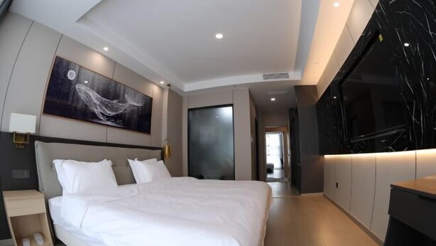 A modern bedroom with a large bed, a wall-mounted TV, and a painting of a whale. - Fenghuangtai Holiday Hotel Junan Lingang Development Zone (Junan County)