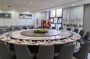 Un salón de conferencias con una mesa redonda, sillas y un centro de mesa decorativo.