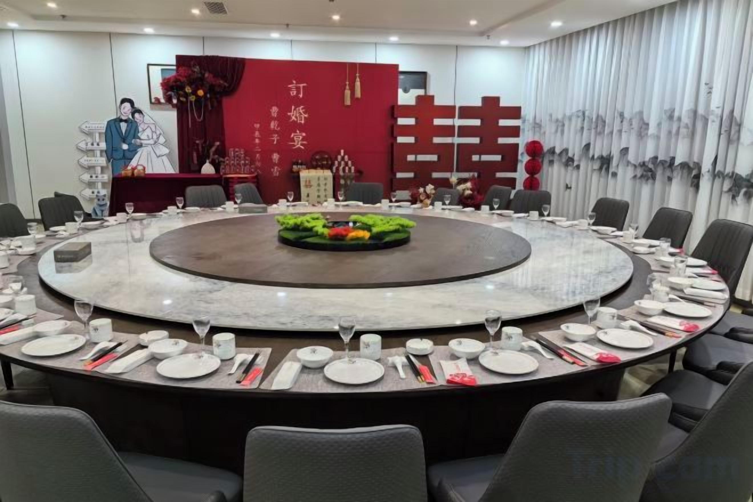 A conference room with a round table, chairs, and a stage with a backdrop.