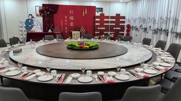 A conference room with a round table, chairs, and a stage with a backdrop.