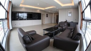 A spacious living area with a modern design, featuring a large black marble backsplash, a central glass coffee table, and a seating area with leather sofas. - Fenghuangtai Holiday Hotel Junan Lingang Development Zone (Junan County)