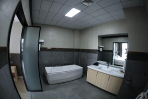 A modern bathroom with a bathtub, a large mirror, and a vanity with a sink. - Fenghuangtai Holiday Hotel Junan Lingang Development Zone (Junan County)