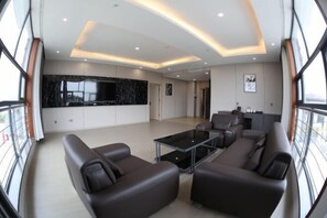 Uma sala de estar espaçosa com design moderno, apresentando uma grande parede de mármore preto, uma mesa de centro de vidro e um espaço de estar com sofás de couro.