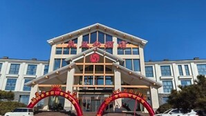A hotel with a prominent entrance and a large red archway. - Fenghuangtai Holiday Hotel Junan Lingang Development Zone (Junan County)