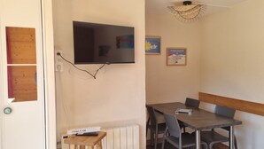 Comedor con mesa y sillas, televisor montado en la pared y un radiador debajo.