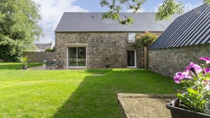A stone house with a sloped roof, a small garden, and a patio area with outdoor furniture. - Single-storey house in Anneville sur Mer with private garden (Gouville-sur-Mer)
