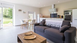 A modern living room with a sofa, coffee table, and dining area. - Single-storey house in Anneville sur Mer with private garden (Gouville-sur-Mer)