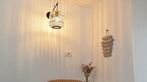 Ein Eckzimmer mit Korbsessel, Pendelleuchte, kleinem Tisch mit Vase und einem an der Wand befestigten Schild.
