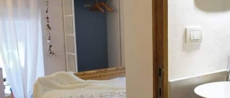 Une chambre à coucher comprenant un lit, une armoire et une salle de bain avec un lavabo et un miroir.