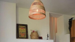Ein Wohnzimmer mit einem gestreiften Sofa, einer gewebten Pendelleuchte, einem gerahmten Kunstwerk und einer Treppe im Hintergrund.