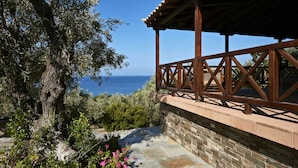 A wooden balcony with stone walls overlooking a clear blue sea. - Skiathos Ira Hotel (Skiathos)