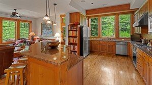Una cocina amplia con armarios de madera, encimera de granito y ventanas grandes que dan a vistas del exterior.
