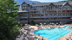 Un resort con una amplia zona de piscina, múltiples tumbonas y un edificio con balcones.