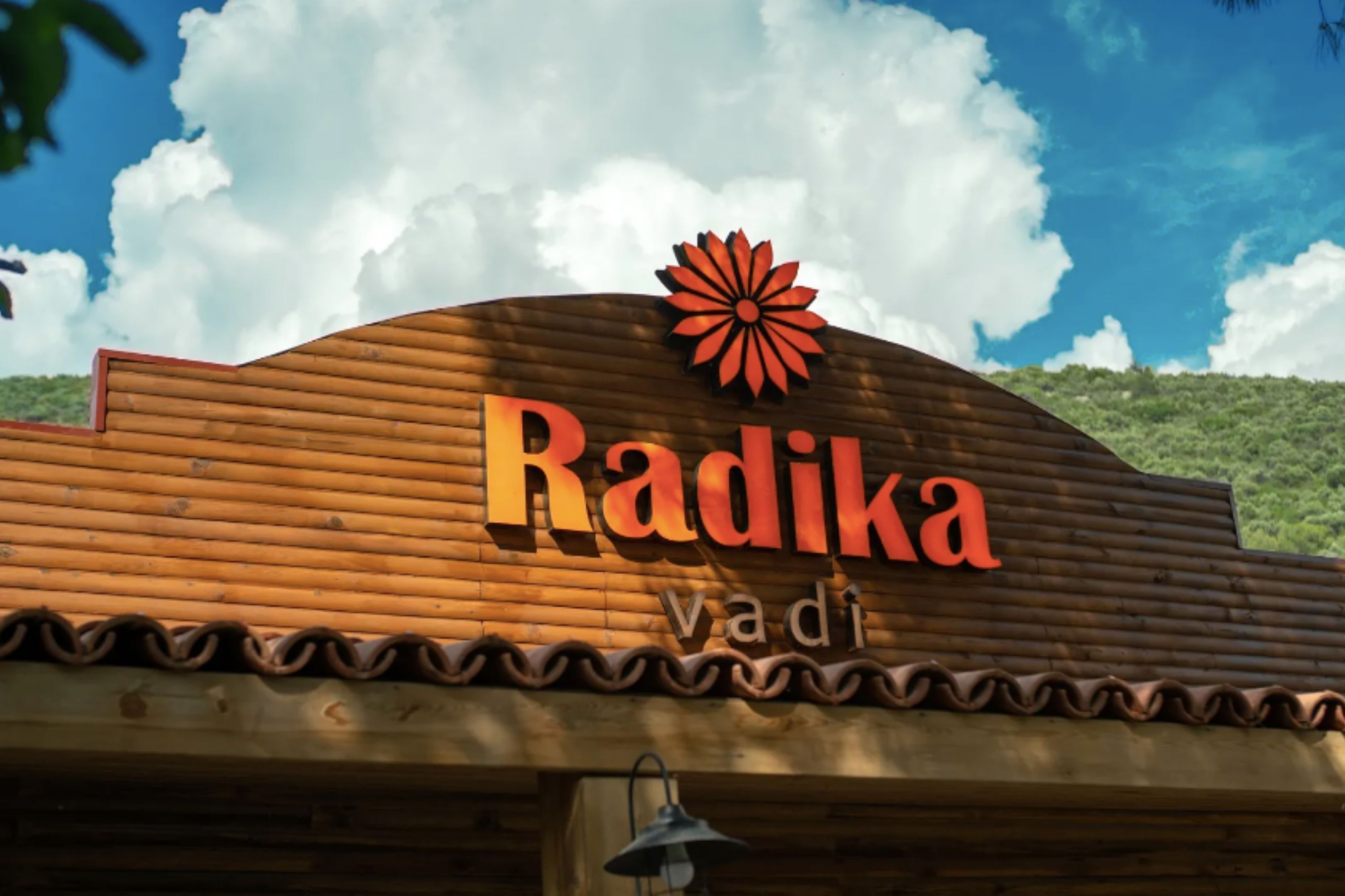 A wooden sign with the name "Radika" and a flower emblem.