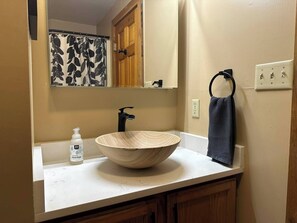 A bathroom with a wooden bowl sink, a black faucet, a bottle of hand soap, a towel ring, and a mirror above the sink. - Rustic Log Cabin with Private Dock on the Lake! (Harpers Ferry)