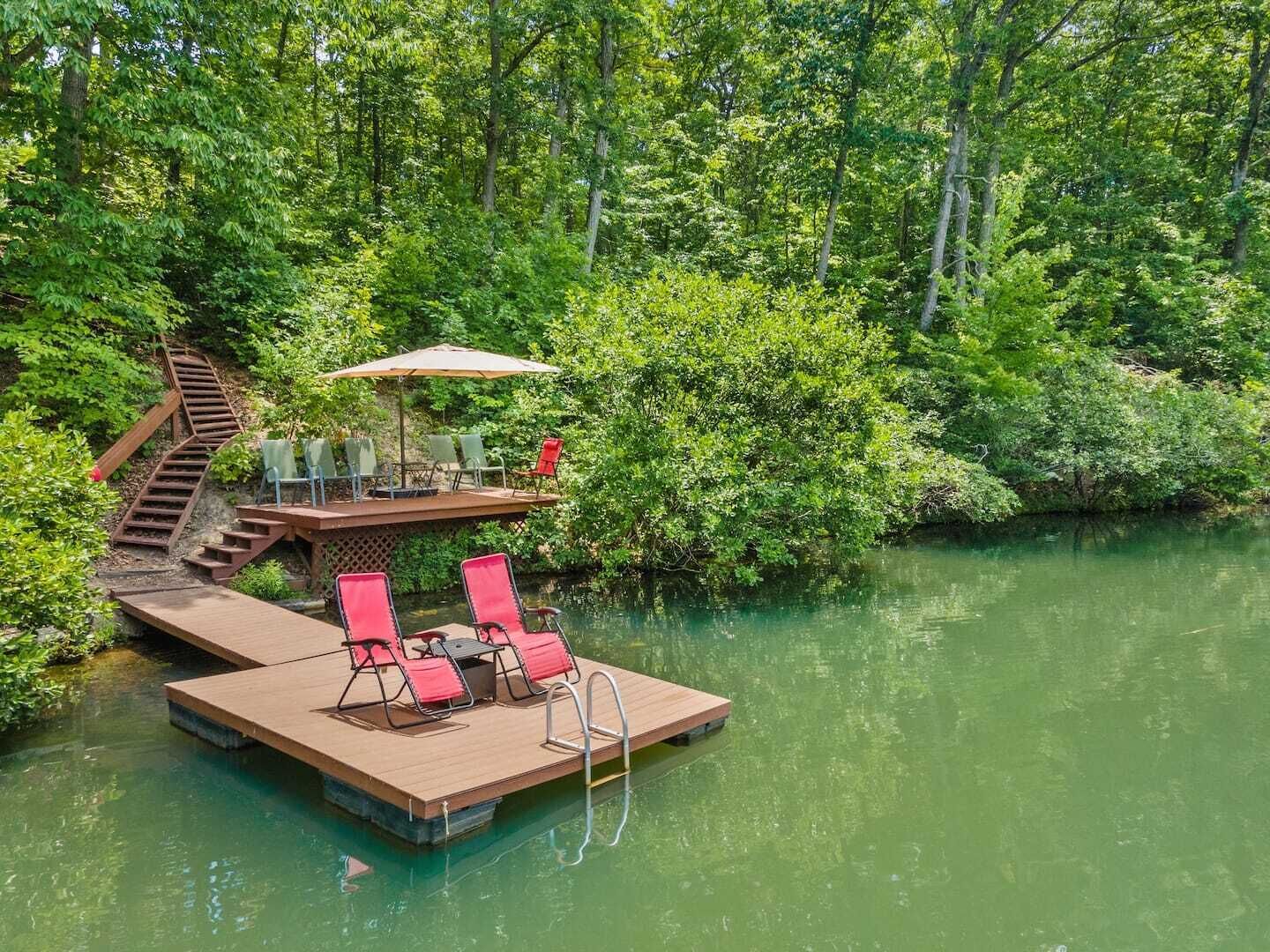 Une terrasse en bois, dotée de mobilier d’extérieur et d’un escalier menant à une plateforme surélevée.