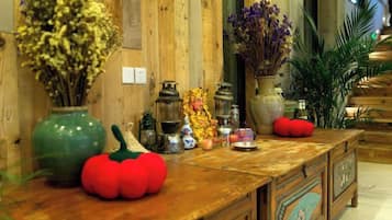 Een houten toonbank met decoratieve objecten, zoals een groene vaas, een rode tomaatvormige decoratie en diverse kleine beeldjes.