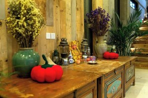 A wooden counter with decorative items, including a green vase, a red tomato-shaped object, and various small figurines. - Hecha Kanyun Lake View Inn (Dali City)