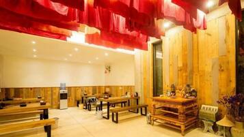 A room with wooden benches and tables, a small kitchen area, and a wooden wall with a door.