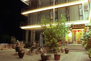 A two-story building with a well-lit entrance, outdoor seating area, and potted plants.