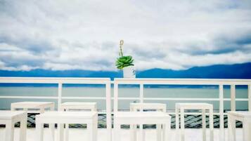 Un balcón blanco con vistas al mar y un cielo nublado.