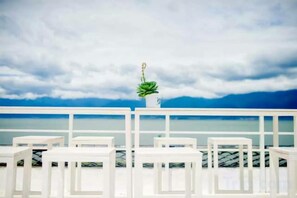 A white balcony with a view of the sea and a cloudy sky.