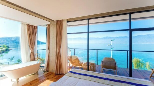 Un dormitorio con una cama grande, una bañera y vistas al mar.