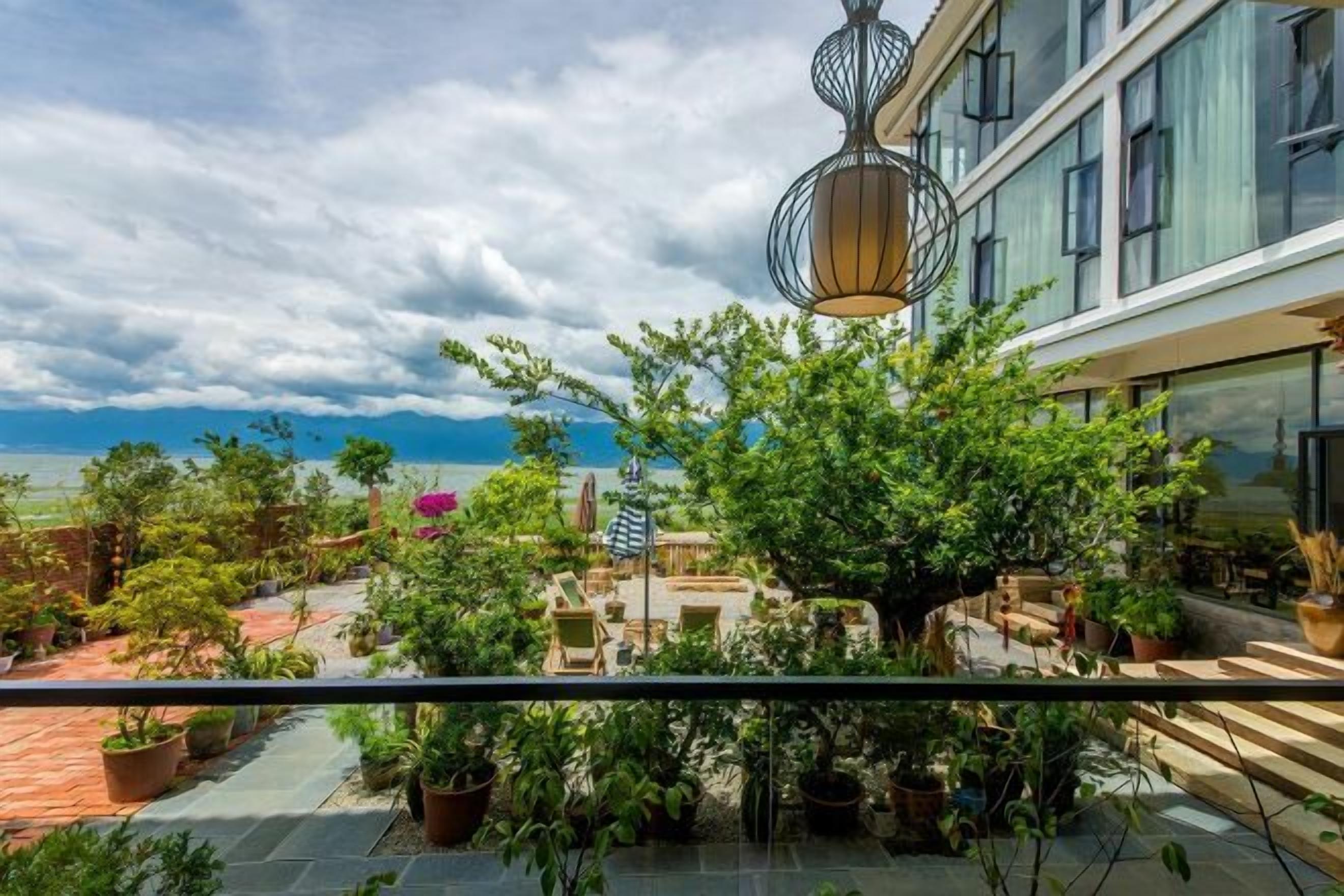 A balcony with potted plants, a hanging light fixture, and a view of the sea.