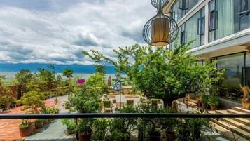 A balcony with potted plants, a hanging light fixture, and a view of the sea.