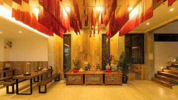 A hotel lobby with a reception desk, benches, and a large mirror.