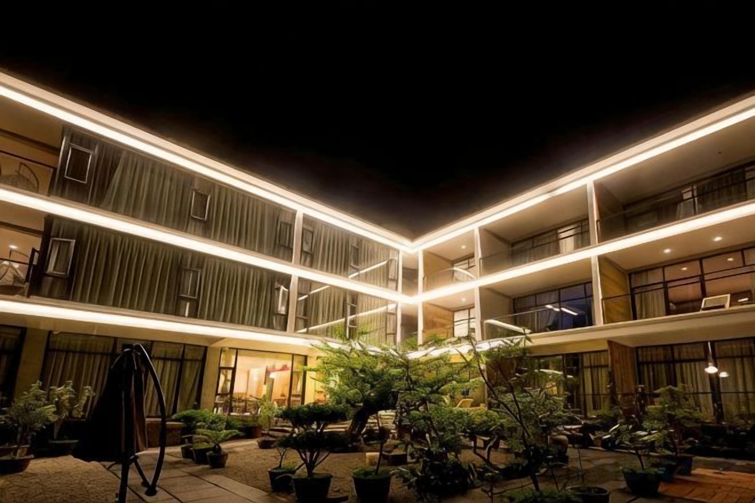 A multi-level hotel with a courtyard featuring potted plants and a swing set.