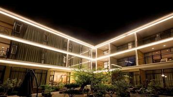 A multi-level hotel with a courtyard featuring potted plants and a swing set.