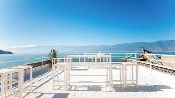 Una terraza frente a la playa, con vistas al mar y a las montañas.