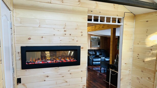 A wooden-paneled room with a fireplace, a leather sofa, and a door leading to another room.