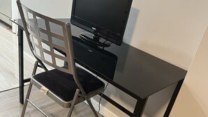 A compact workspace with a black desk, a chair, and a television.