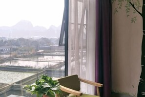 Quarto com vista para um rio, uma cadeira e um vaso de planta.