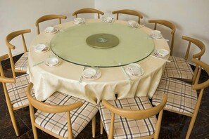 Mesa redonda con tope de vidrio verde rodeada por seis sillas con cojines a cuadros.