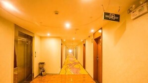 En hotelgang med marmorgulv, elevator og nødudgangsskilte.