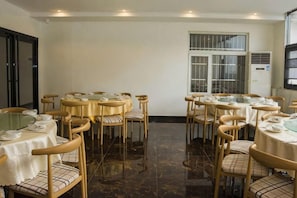 Un salón de conferencias con mesas redondas, sillas y un amplio ventanal.