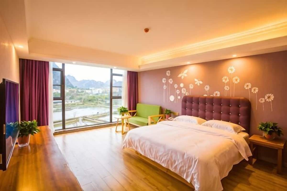 Habitación de hotel con una cama grande, televisión, escritorio y vistas a la ciudad.