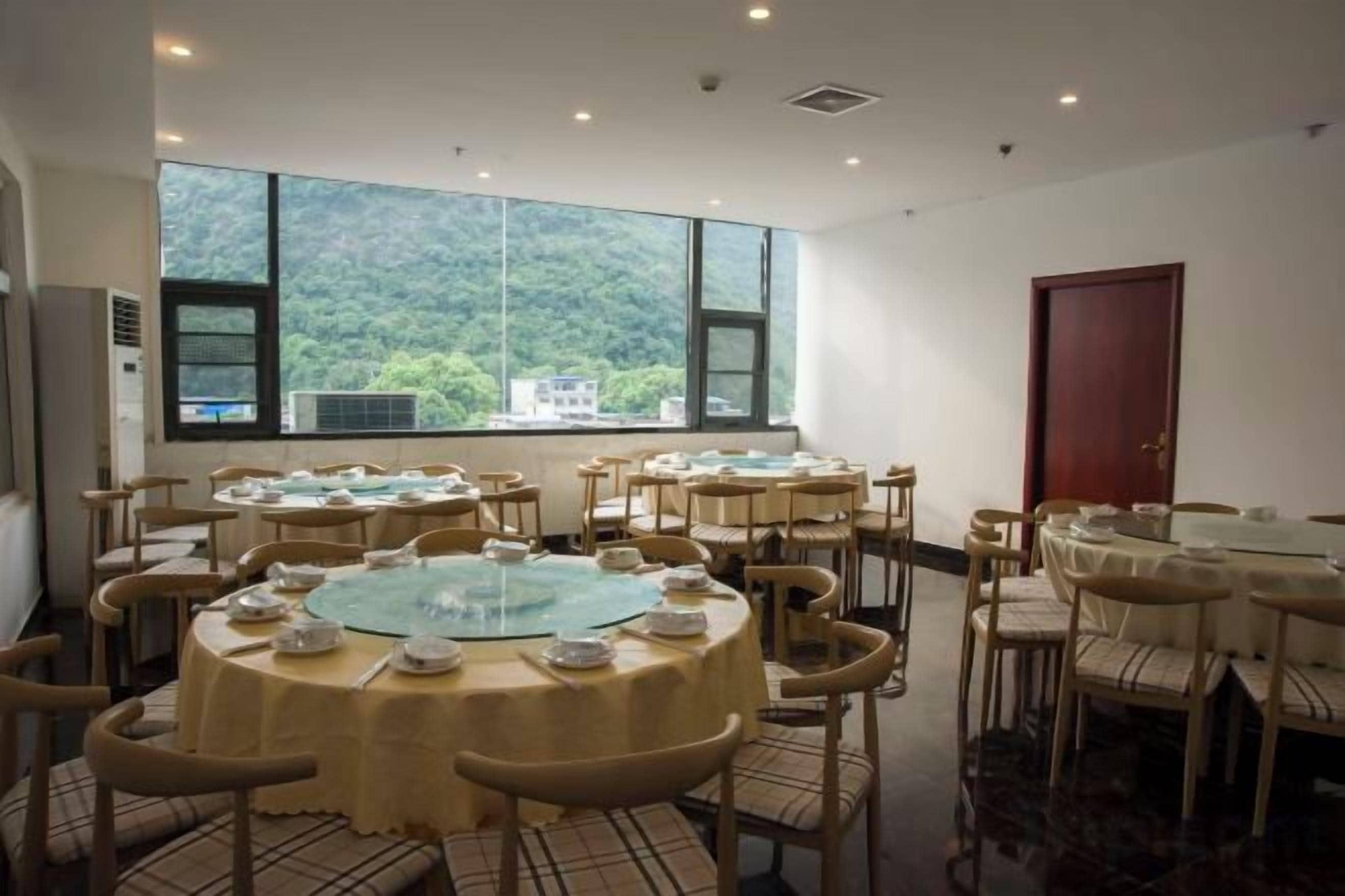 Un comedor con mesas redondas, sillas y un ventanal con vistas a la montaña.