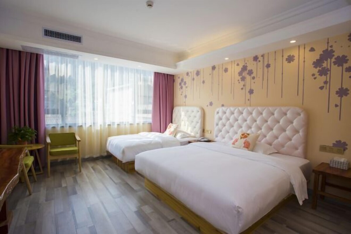 A hotel room with two beds, a desk, a chair, and a window with curtains.