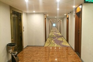 A long, well-lit hallway with a patterned carpet, elevators, and doors on both sides. - Tao Flute Hotel (Guilin)