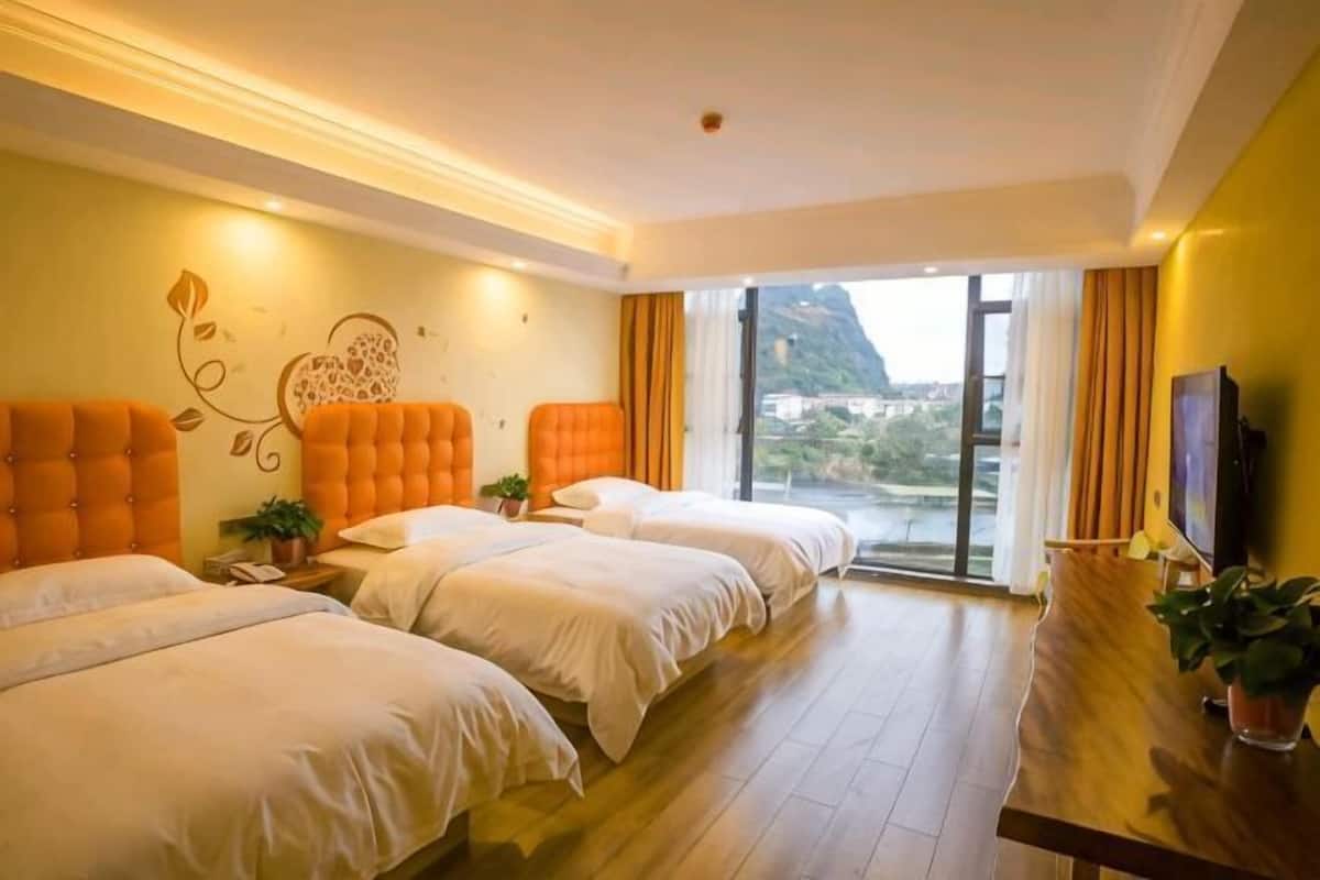 Habitación de hotel con dos camas, un escritorio de madera, televisión y un ventanal con vistas a la ciudad.