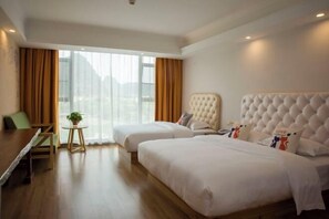 A hotel room with two beds, a dining table, a small round table with a plant, and large windows with curtains. - Tao Flute Hotel (Guilin)